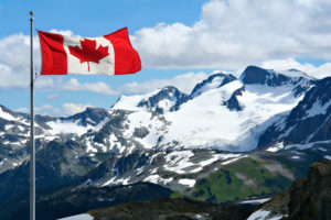 A canadian flag flying over the mountains.