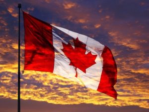 A canadian flag flying in the wind at sunset.