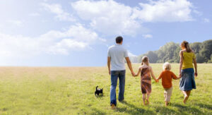 A man and woman holding hands while walking their dog.